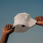 Bucket hat mock-up taken by a person with his two hands and a blue sky behind
