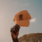 A hand from a black guy holding a hat mock-up in a desert environment