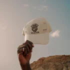 A hand from a black guy holding a hat mock-up in a desert environment