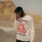 African-american man wearing a jumper mock-up in a desert environment while he is hiding his face with his hand