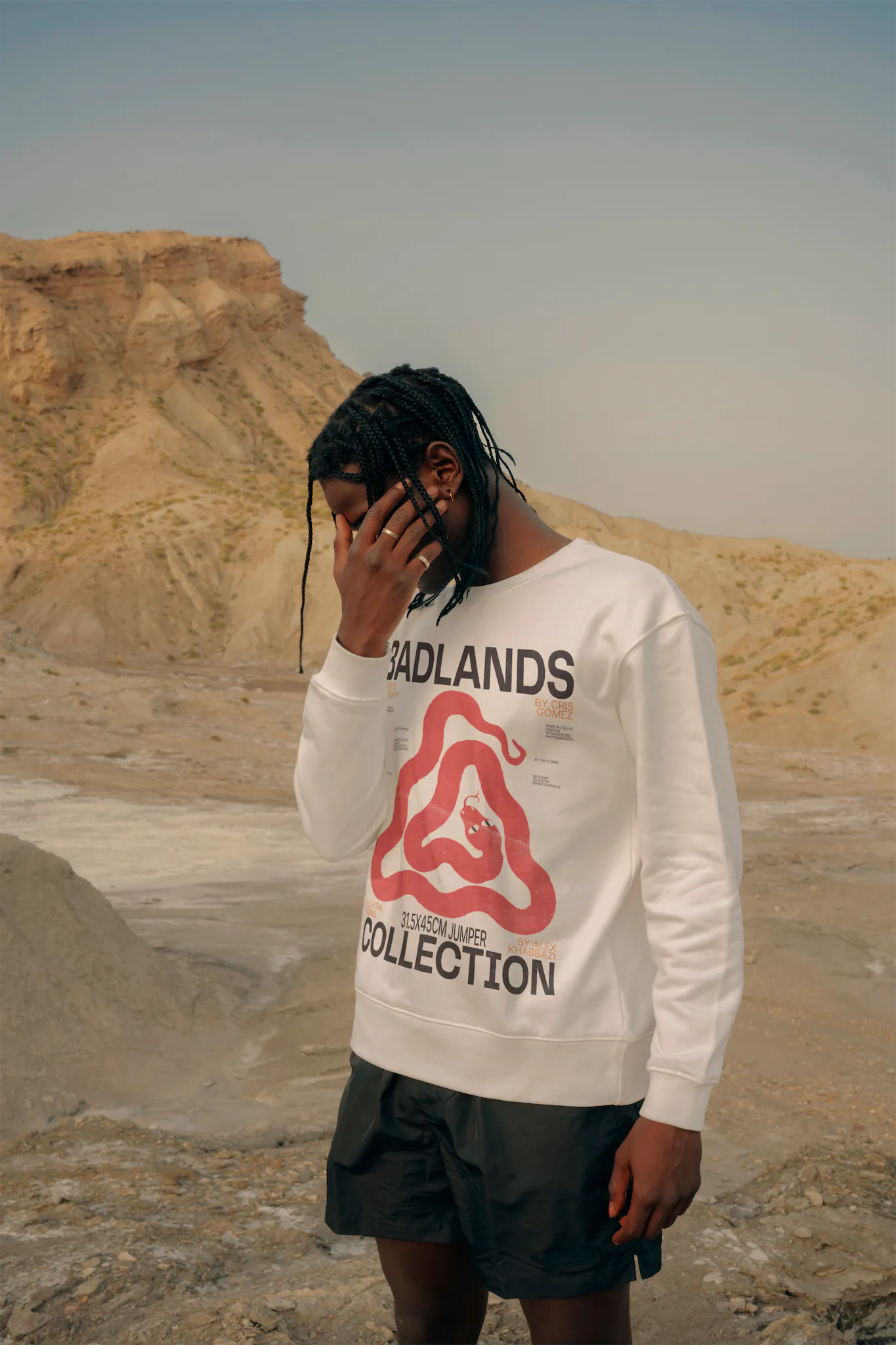 African-american man wearing a jumper mock-up in a desert environment while he is hiding his face with his hand