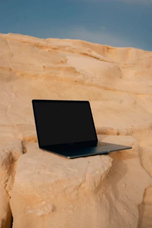 Macbook pro mock-up on a rocky surface with a blue sky behind