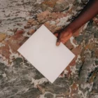A hand from a black guy holding a magazine mock-up over a rocky surface
