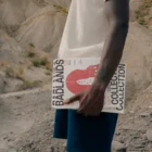 Dark-skinned person holding several magazine mock-ups in a desert environment
