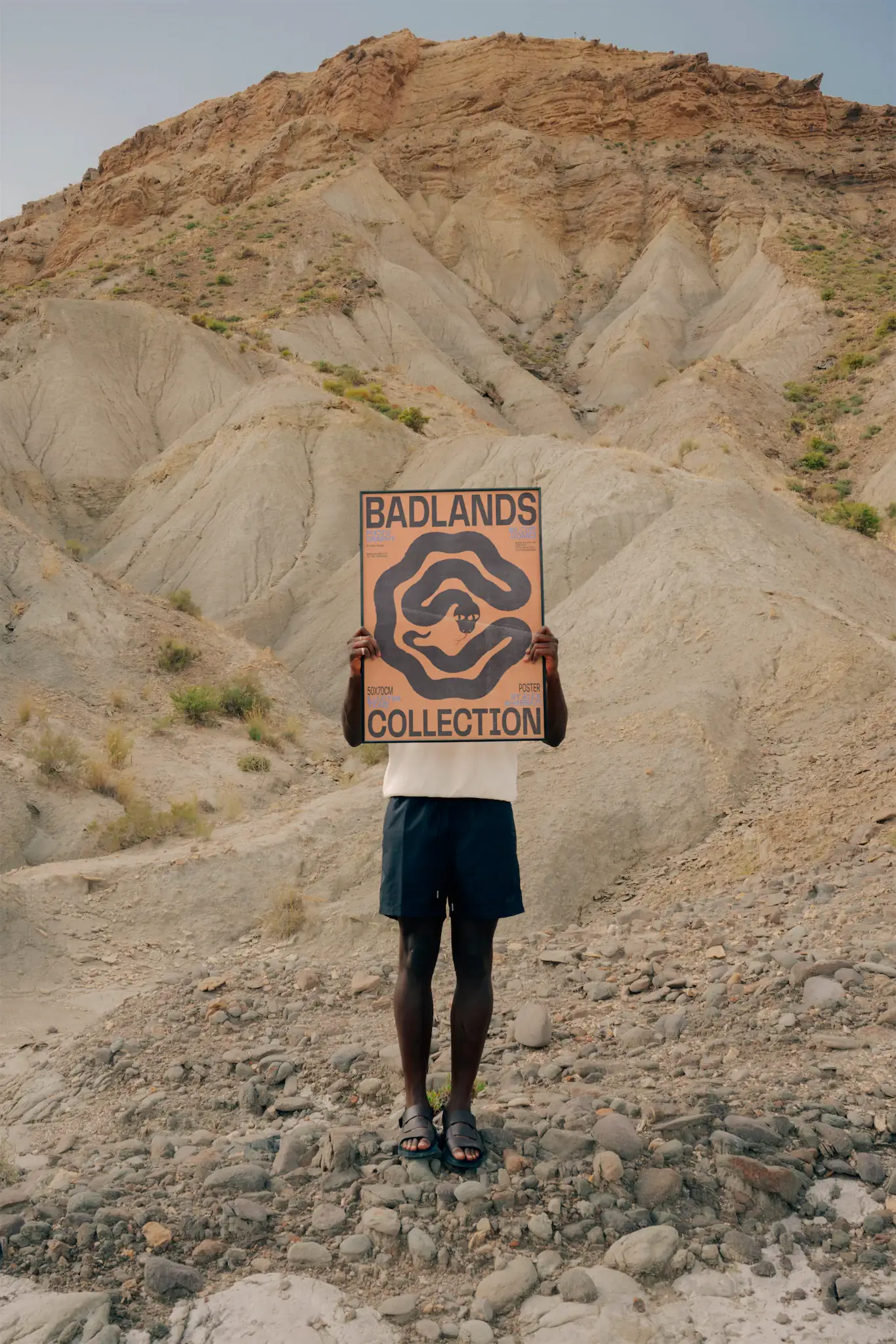 Black guy holding a framed poster mock-up in a desert environment