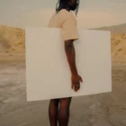 Black person holding a poster mock-up in a desert environment