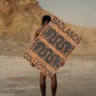 African-american person from behind holding a poster mock-up in a desert environment