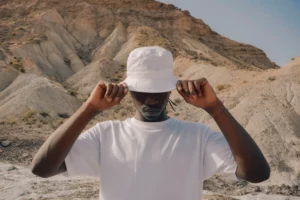 Black guy wearing a bucket hat mock-up and a t-shirt mock-up in a desert environment