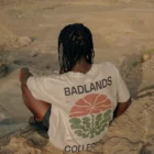 Young black man from behind sitting and wearing a t-shirt mock-up in a desert environment