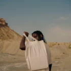 Young black man from behind holding a tote bag mock-up in a desert environment