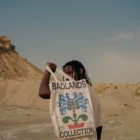 Young black man from behind holding a tote bag mock-up in a desert environment
