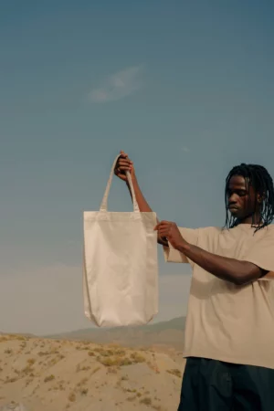 Black person holding a tote bag mock-up in a desert environment