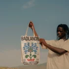 Black person holding a tote bag mock-up in a desert environment