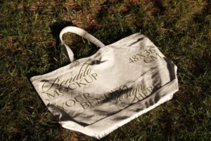 Tote bag mockup on the grass with natural light.