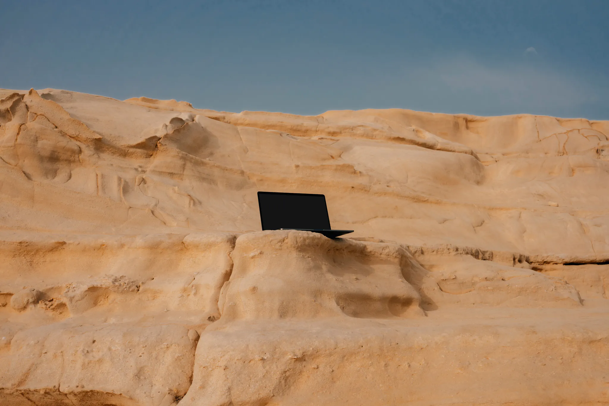Macbook Pro device mockup freebie placed in natural rocks in the beach.