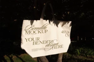 Tote bag mockup freebie hanging from the branch of a tree.