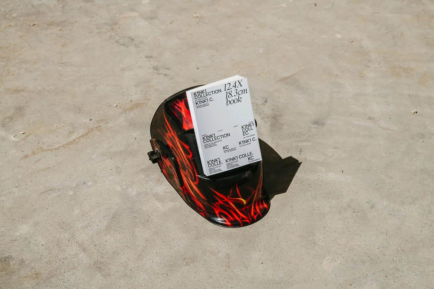 Paperback book mockup on a red helmet placed on an industrial floor.