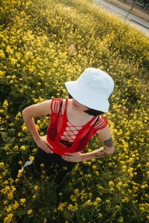 Bucket hat mockup worn by a female model in a yellow flowers field. The photography has vertical orientation.