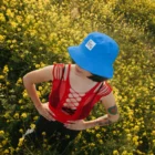 Bucket hat mockup worn by a female model in a yellow flowers field. The photography has vertical orientation.