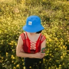 Bucket hat mockup worn by a female model in a yellow flowers field. The photography has horizontal orientation.