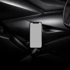 Creative iPhone mockup placed on the black surface of a motorbike.