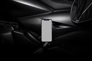 Creative iPhone mockup placed on the black surface of a motorbike.