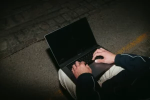 Macbook Pro mockup in the lap of a young guy wearing urban streetwear.