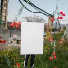 Creative poster mockup grabbed by a girl in the middle of a flower field.