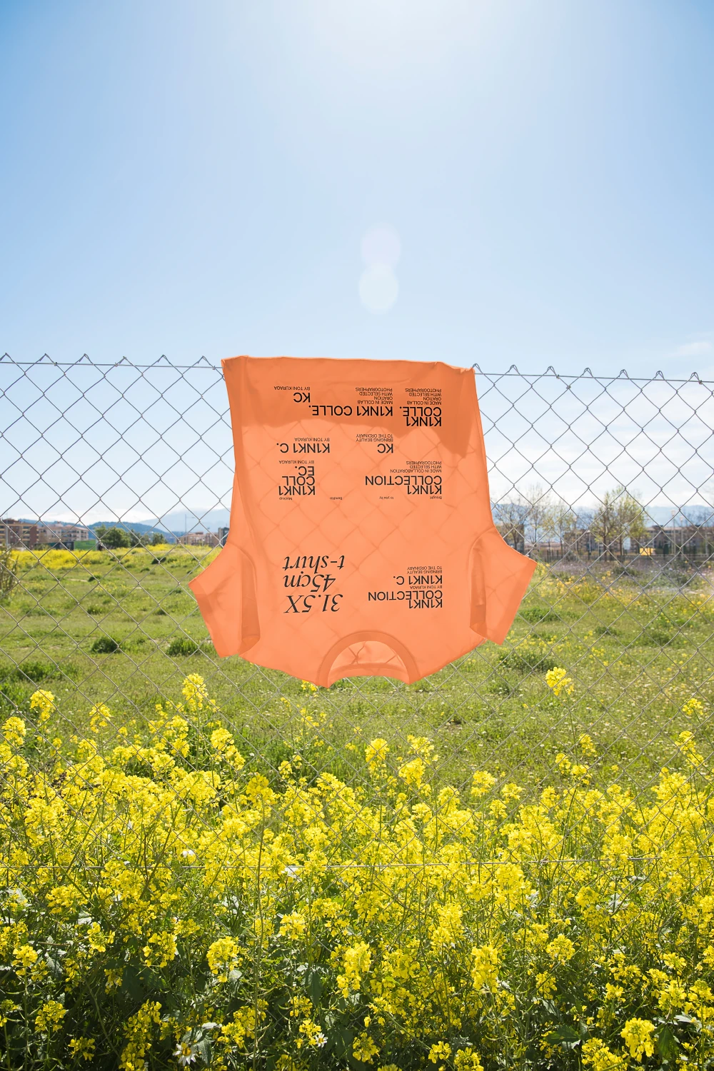 Urban t-shirt mockup hanging in a fence in the midst of a flower field.