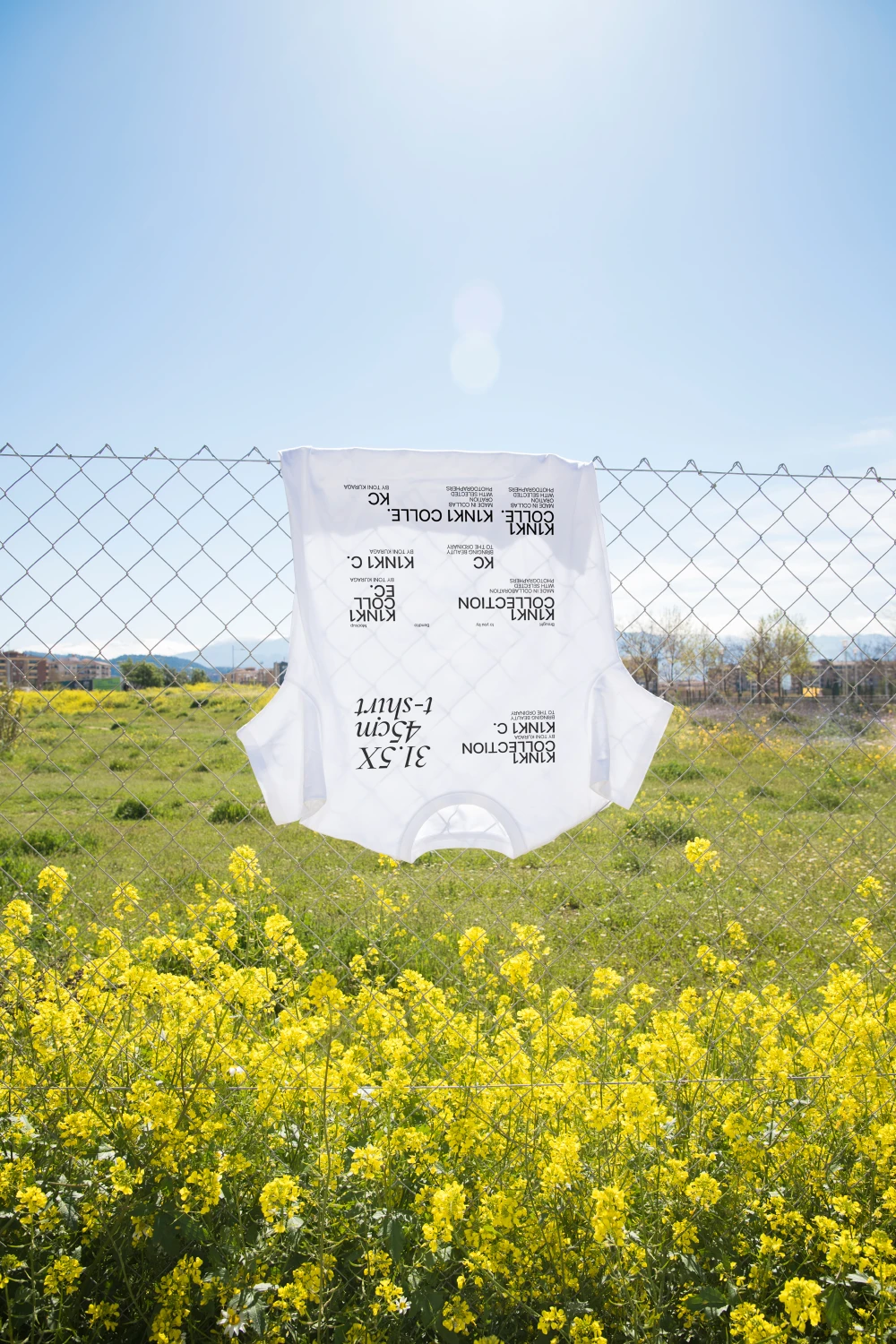 Urban t-shirt mockup hanging in a fence in the midst of a flower field.
