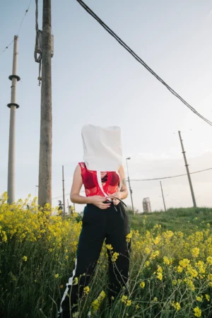 Urban tote bag mockup covering the face of a girl in a flower field.