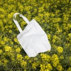 Urban tote bag mockup placed on a yellow flower field.