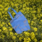 Urban tote bag mockup placed on a yellow flower field.
