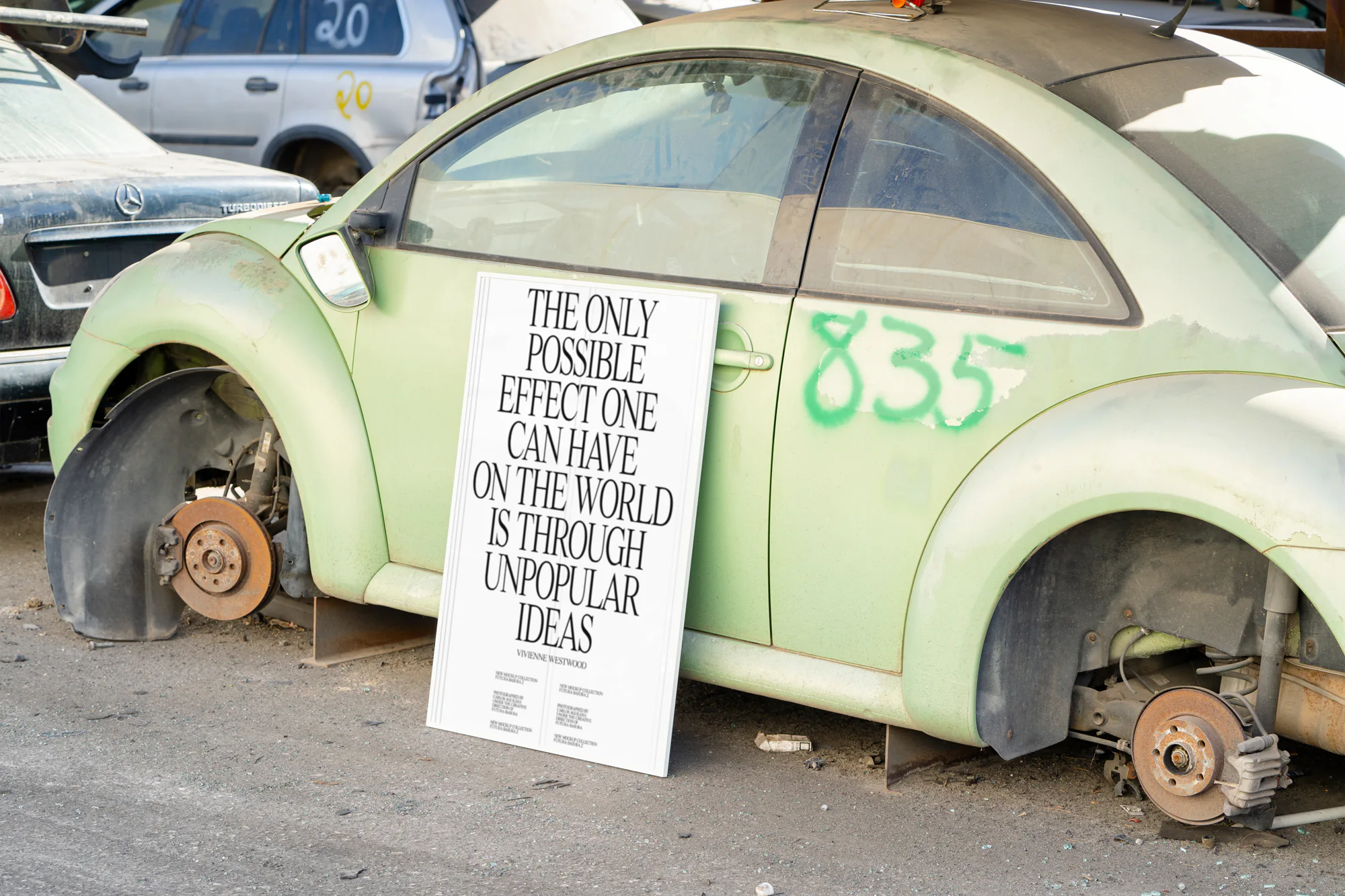 Framed poster mockup next to a green beetle car in a car scrapping including a Vivienne Westwood quote