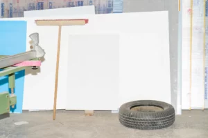 61x91cm poster mockup in between a broom and a car wheel in an industrial context