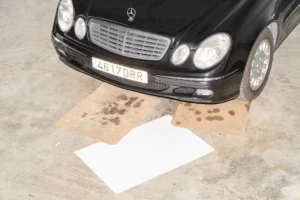 Poster mockup on the floor with 2 dirty cardboards on top in front of a luxury car