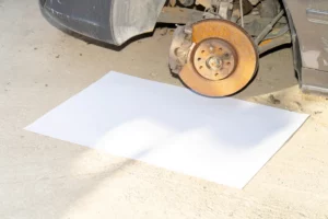 Poster mockup on the ground under a car without a wheel