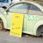 Framed poster mockup next to a green beetle car in a car scrapping