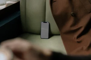 Iphone mockup on top of a green leather seat next to a brown coat