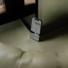 Iphone mockup behind a green leather couch next to a mirror