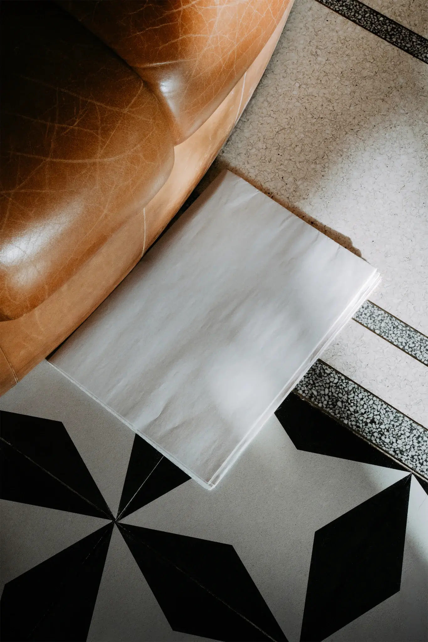 Folded newspaper mockup on a floor with patterns next to a fancy leather couch