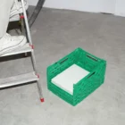 Magazine mockup inside a green plastic box over a concrete floor near a person who is on a ladder