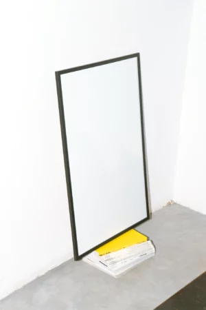 Framed mockup on top of a block of books with a white wall behind