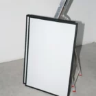 Set of framed poster mockups leaning against a ladder in a room with white walls and concrete floor