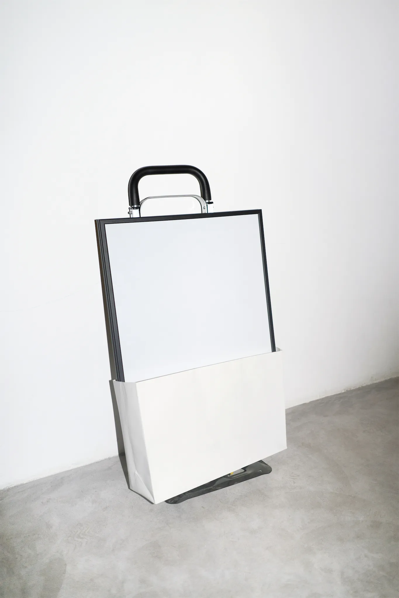61x91cm poster mockup inside a shopping bag which is on a trolley over a concrete floor and white walls around
