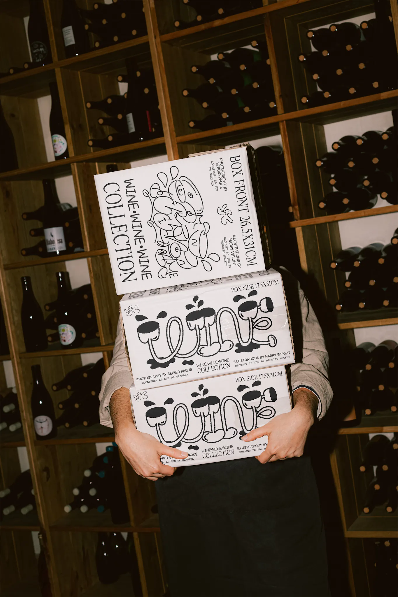 PSD mockup of a woman holding a pile of cardboard boxes. The boxes are rectangular and are place in the interior of a wine cellar. Wine packaging mockup. Wine shop mockup. Restaurant mockup.