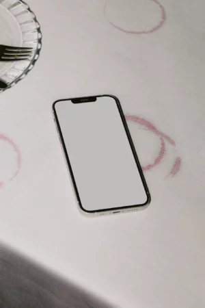 iPhone PSD mockup on top of a white tablecloth stained with wine marks. Wine branding mockup. Restaurant merchandising mockup. Device mockups.
