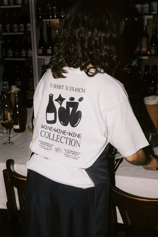 White t-shirt back PSD mockup. T-shirt mockup being worn by a woman in the interior of a restaurant. Wine merchandising mockup. Restaurant mockup. Wine bar mockup. Fashion and apparel mockup.