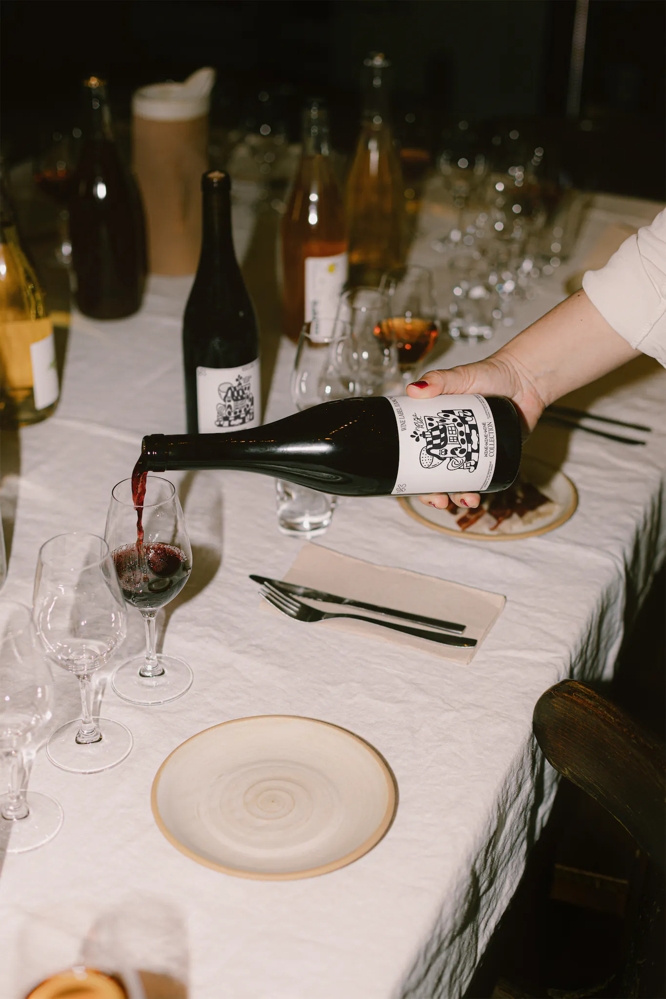 Wine label PSD mockup. Wine being poured from a bottle mockup. Wine bottle mockup in a restaurant table full of meals and dishes. Wine packaging mockup. Restaurant mockup. Wine bar mockup.