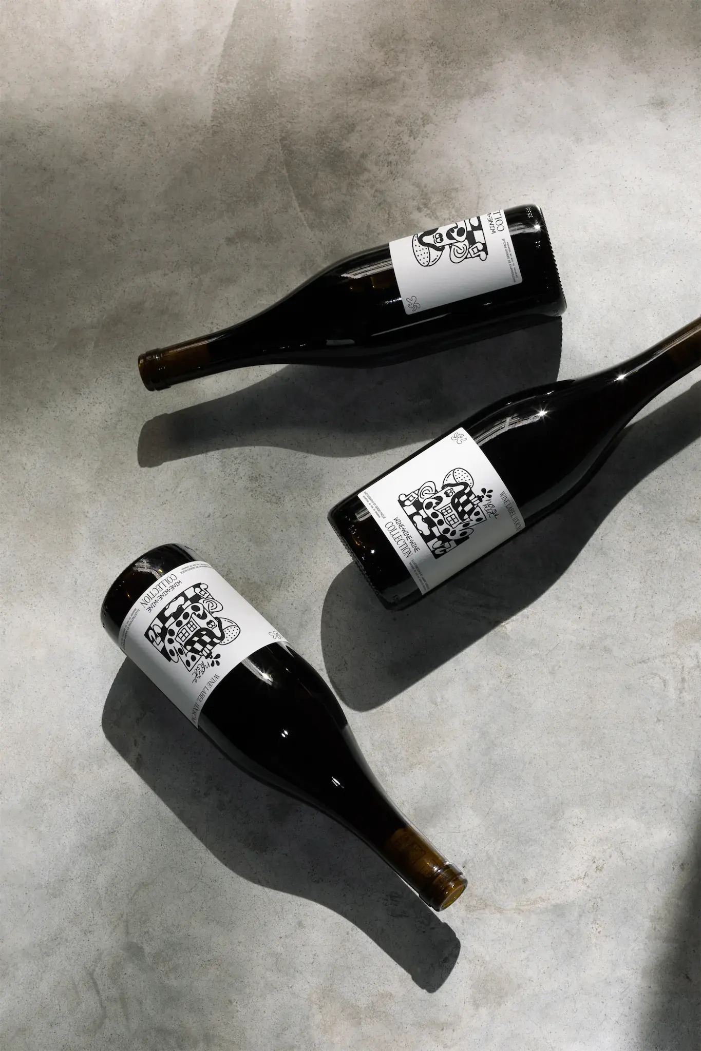 Wine label PSD mockup. Wine bottle mockup resting on a concrete floor. Three wine bottles placed in different positions, with a ray of light resting on them. Wine packaging mockup. Restaurant mockup. Wine bar mockup. Wine shop mockup.